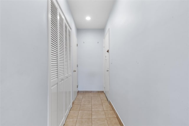 corridor with light tile patterned floors, baseboards, and recessed lighting