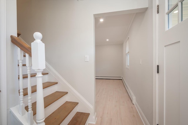 staircase with baseboard heating, a baseboard radiator, baseboards, and wood finished floors