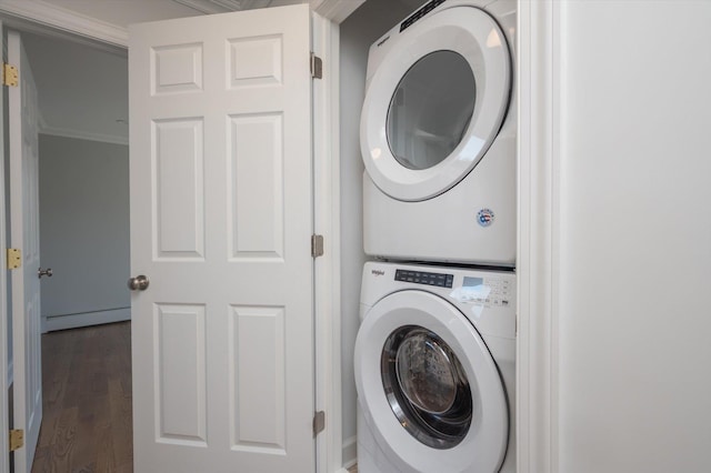 washroom with a baseboard heating unit, laundry area, dark wood-type flooring, stacked washer / drying machine, and ornamental molding