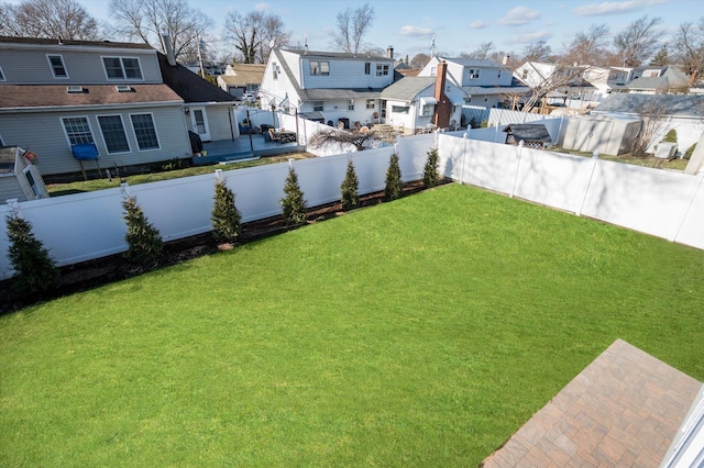 view of yard with driveway, a fenced backyard, and a residential view