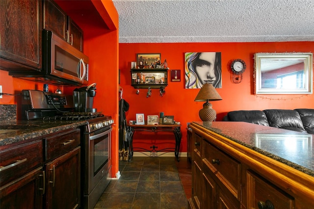 kitchen with a textured ceiling, stainless steel appliances, dark tile patterned floors, and baseboards