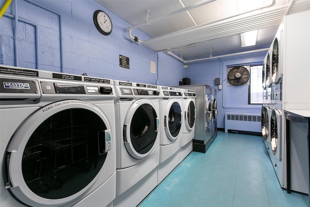 common laundry area featuring concrete block wall, stacked washer and dryer, radiator heating unit, and separate washer and dryer