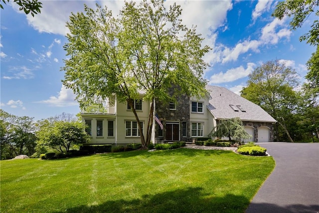 view of front of home with a garage, stucco siding, a front lawn, and aphalt driveway