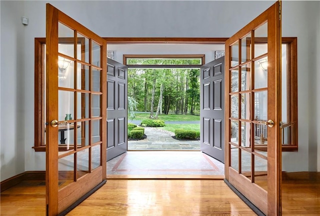 doorway with light wood-type flooring, baseboards, and french doors