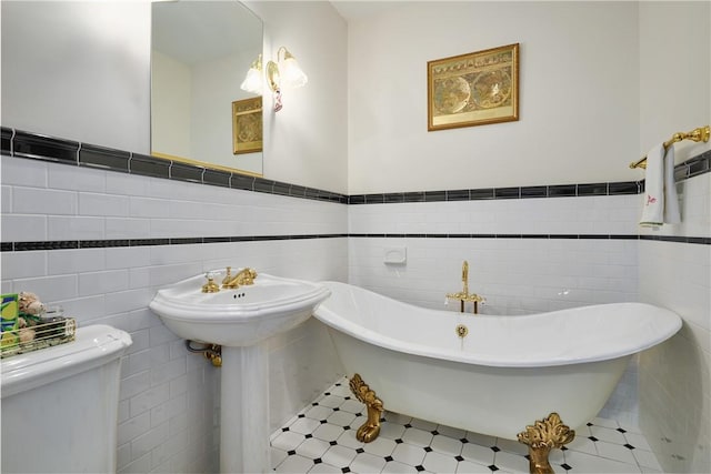 bathroom featuring toilet, a freestanding bath, and wainscoting