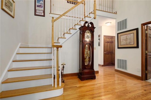 staircase with visible vents, baseboards, and wood finished floors