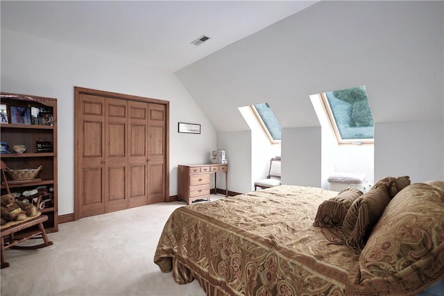 carpeted bedroom featuring vaulted ceiling with skylight, a closet, visible vents, and baseboards