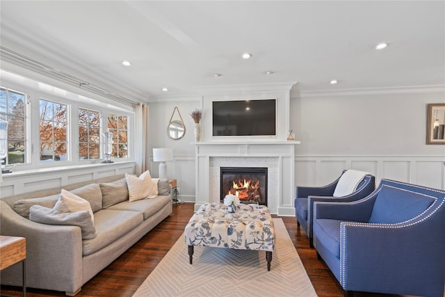 living room featuring recessed lighting, a decorative wall, dark wood finished floors, ornamental molding, and a glass covered fireplace