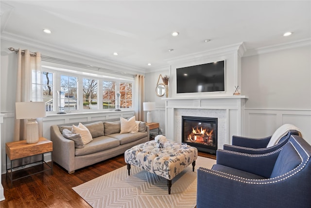 living area featuring recessed lighting, a decorative wall, dark wood-style flooring, ornamental molding, and a glass covered fireplace