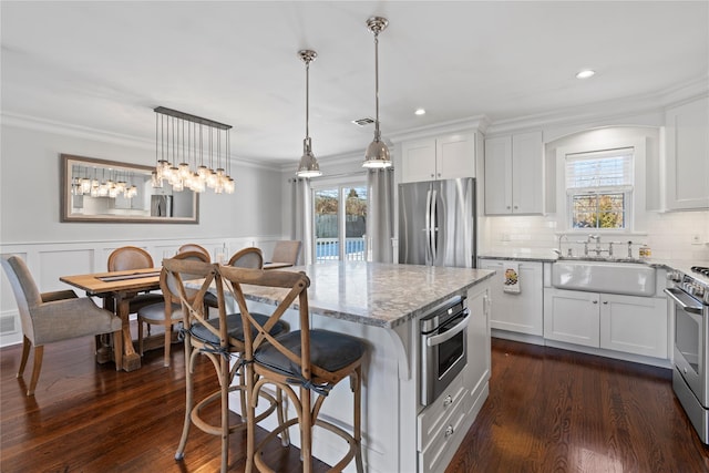 kitchen with hanging light fixtures, appliances with stainless steel finishes, white cabinets, and a sink