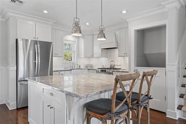 kitchen featuring a center island, custom exhaust hood, visible vents, appliances with stainless steel finishes, and white cabinetry