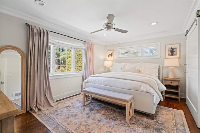 bedroom with a barn door, visible vents, dark wood-style flooring, and ornamental molding