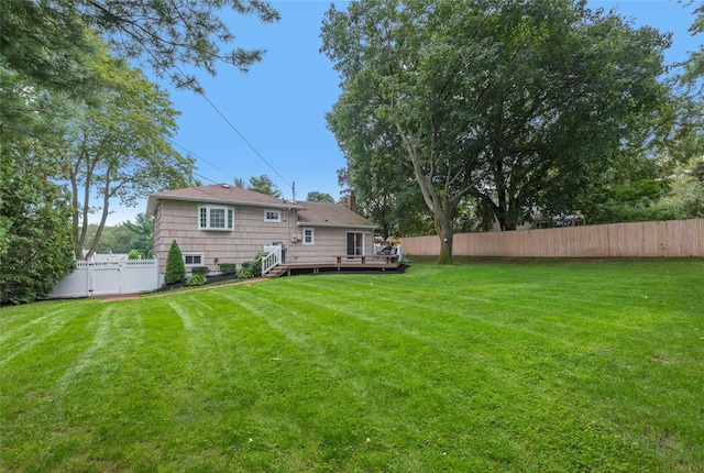 rear view of property with a yard, fence, and a wooden deck