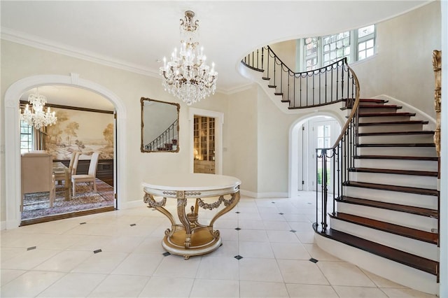 foyer with stairs, arched walkways, ornamental molding, and an inviting chandelier