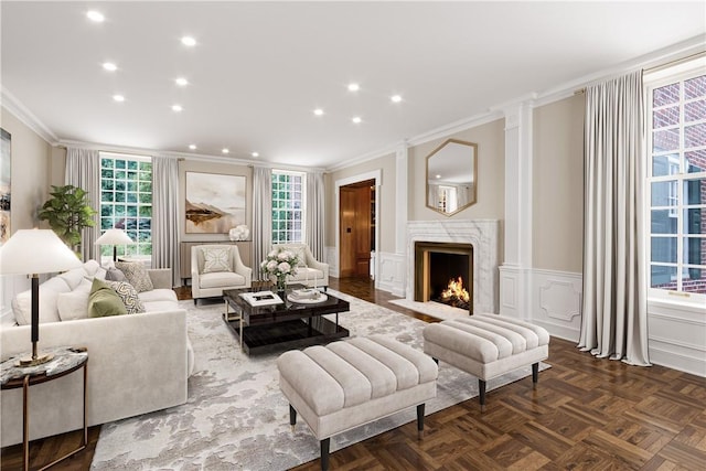 living area with a high end fireplace, wainscoting, crown molding, a decorative wall, and recessed lighting