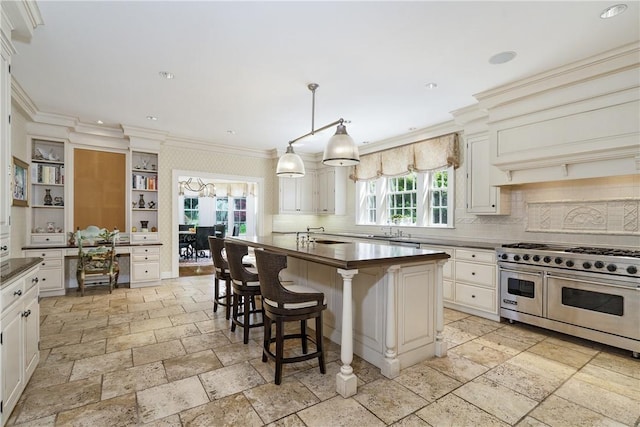 kitchen featuring ornamental molding, double oven range, dark countertops, stone tile flooring, and pendant lighting