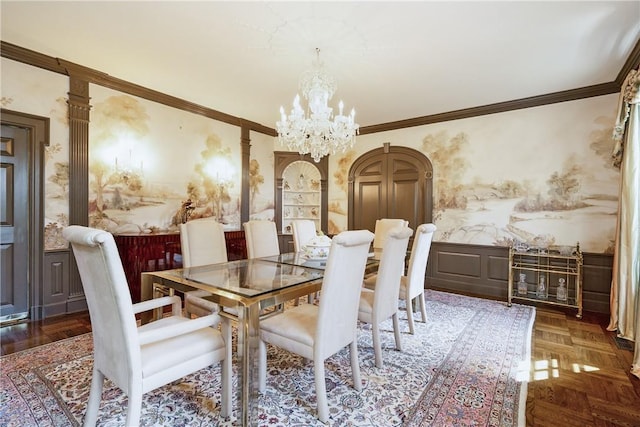 dining room featuring crown molding, wainscoting, a notable chandelier, and wallpapered walls