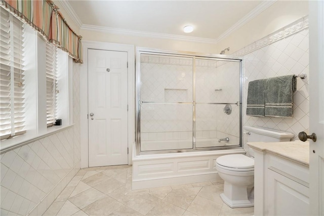 bathroom with toilet, shower / bath combination with glass door, crown molding, vanity, and tile walls