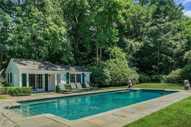 pool with a patio, an outbuilding, a lawn, and an exterior structure