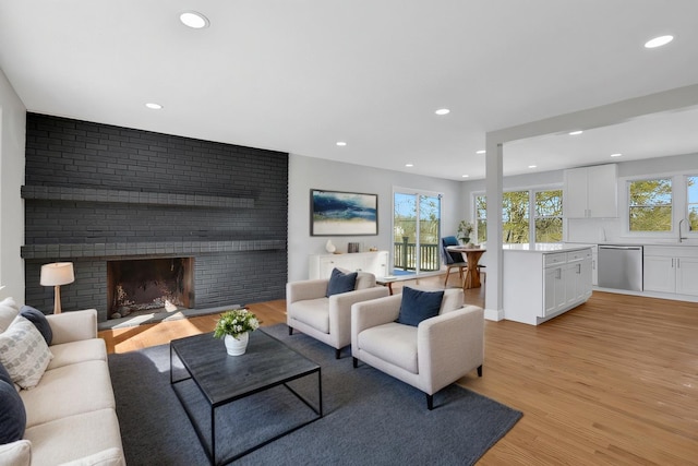 living area with a brick fireplace, light wood-style flooring, and recessed lighting