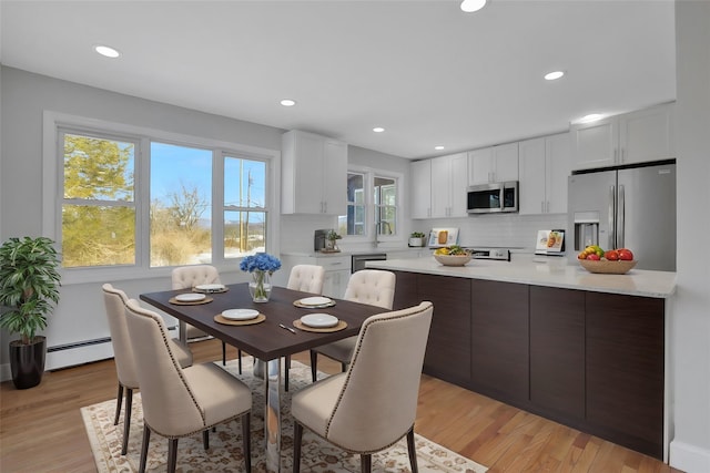 dining space featuring light wood-style flooring, a baseboard heating unit, and recessed lighting