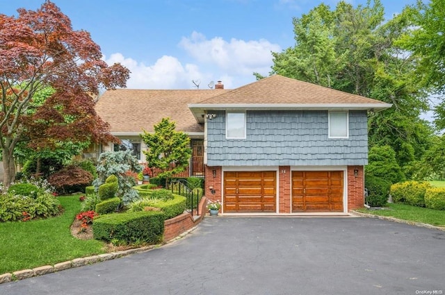 tri-level home featuring brick siding, driveway, a chimney, and an attached garage