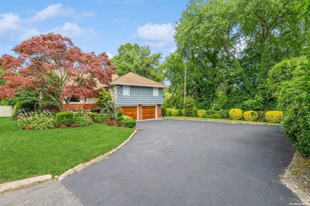 view of front facade featuring aphalt driveway, a front yard, and an attached garage