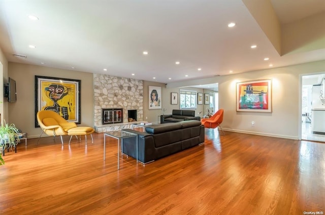 living room featuring recessed lighting, visible vents, a fireplace, and wood finished floors