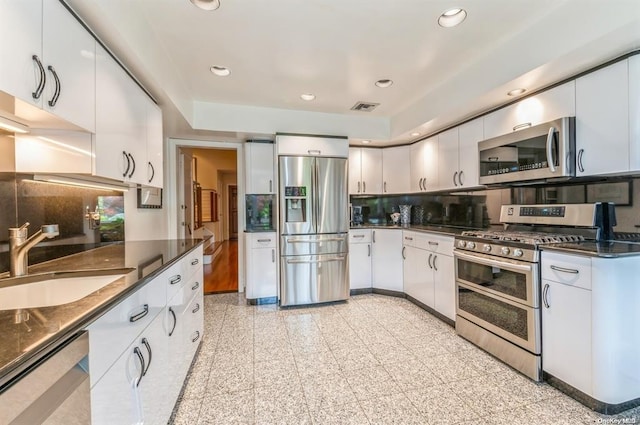 kitchen with stainless steel appliances, recessed lighting, dark countertops, visible vents, and a sink