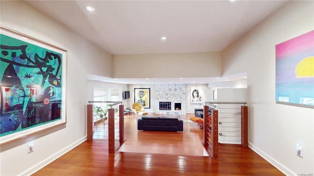 interior space featuring recessed lighting, a stone fireplace, baseboards, and wood finished floors