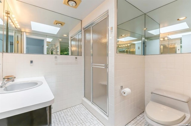 bathroom with a stall shower, toilet, tile patterned flooring, vanity, and tile walls