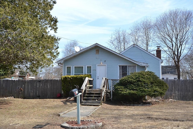 bungalow featuring a chimney and fence