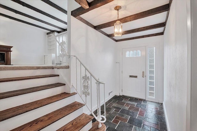 entryway featuring stairs, beam ceiling, stone tile flooring, and baseboards