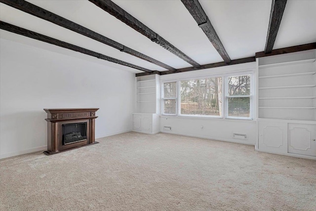 unfurnished living room with built in shelves, beam ceiling, a fireplace, carpet flooring, and baseboards