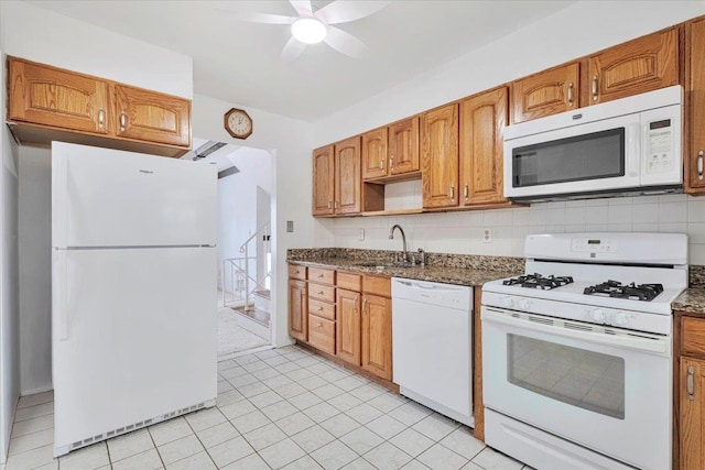 kitchen with white appliances, backsplash, a sink, and brown cabinets