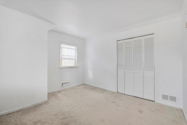 unfurnished bedroom featuring carpet floors, a closet, visible vents, and baseboards