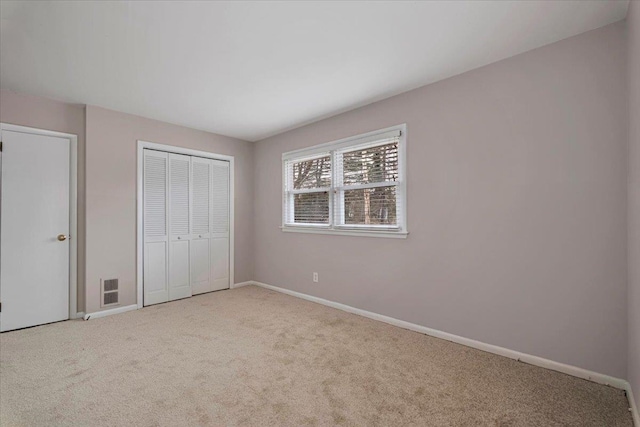 unfurnished bedroom featuring a closet, carpet flooring, visible vents, and baseboards