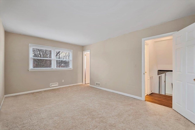 spare room with carpet floors, visible vents, and baseboards