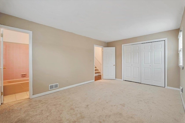 unfurnished bedroom with a closet, carpet flooring, visible vents, and baseboards