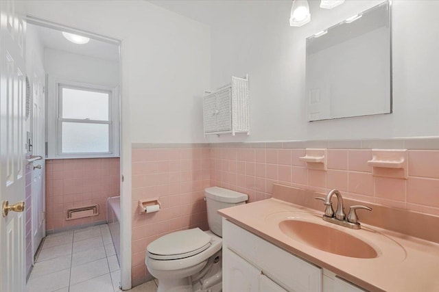 bathroom with toilet, tile patterned floors, vanity, wainscoting, and a tub