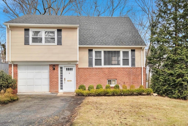 view of front of home with brick siding, roof with shingles, a front lawn, and aphalt driveway