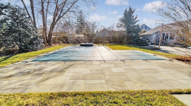 view of swimming pool featuring a yard, a covered pool, and a patio