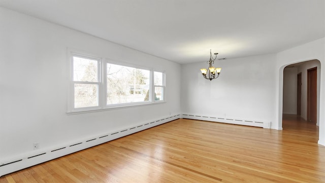 empty room featuring arched walkways, light wood-style flooring, baseboard heating, and an inviting chandelier