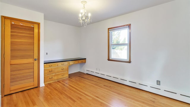 unfurnished room featuring a baseboard radiator, an inviting chandelier, and wood finished floors