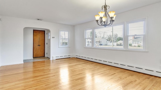 spare room with visible vents, arched walkways, baseboard heating, light wood-style floors, and a notable chandelier