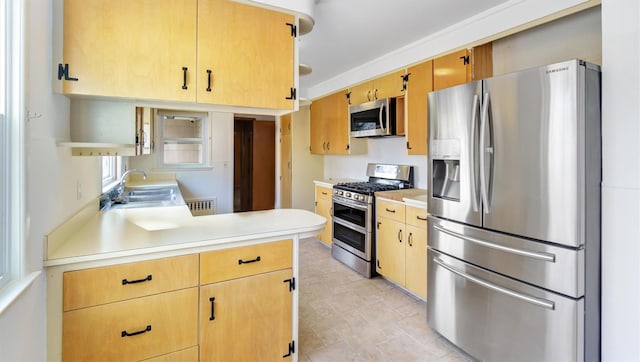 kitchen featuring appliances with stainless steel finishes, a peninsula, light countertops, open shelves, and a sink