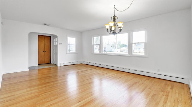 unfurnished room featuring arched walkways, wood finished floors, visible vents, and a chandelier