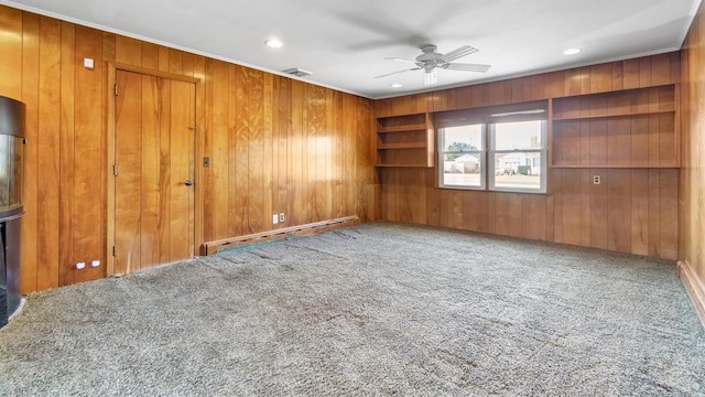 unfurnished room featuring carpet flooring, ceiling fan, wooden walls, and baseboard heating