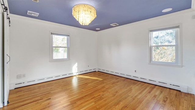 unfurnished room with a chandelier, light wood finished floors, a barn door, and visible vents