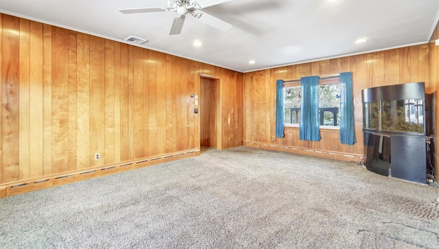 spare room with wooden walls, visible vents, a baseboard radiator, crown molding, and carpet floors